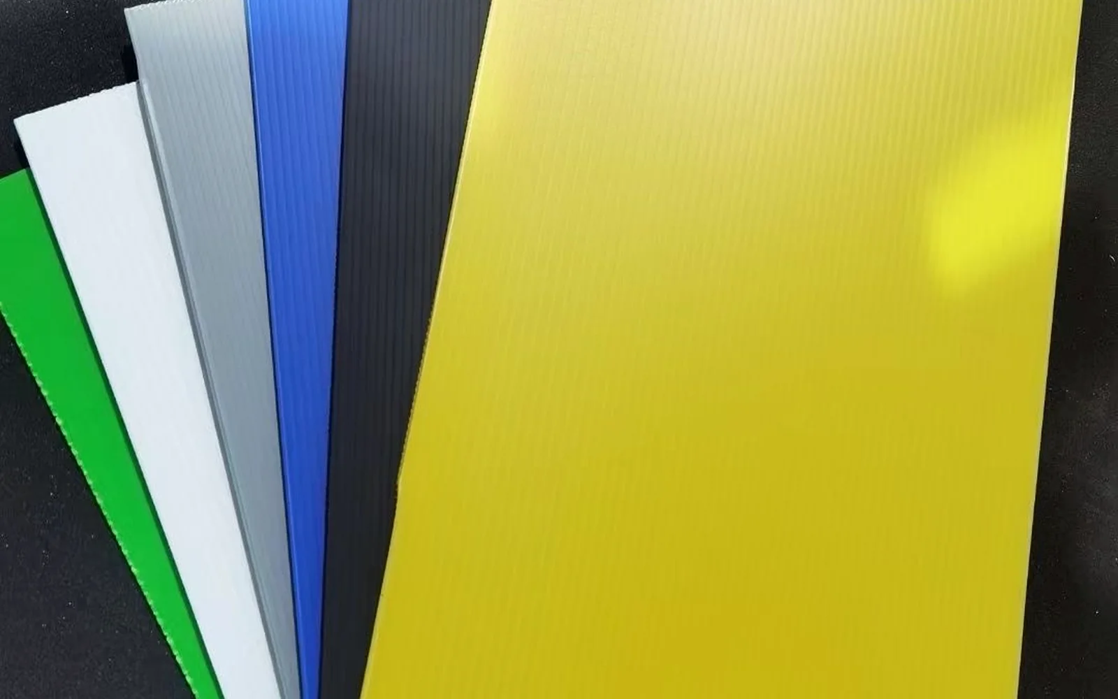 Corrugated polypropylene sheet color samples arranged on a dark surface