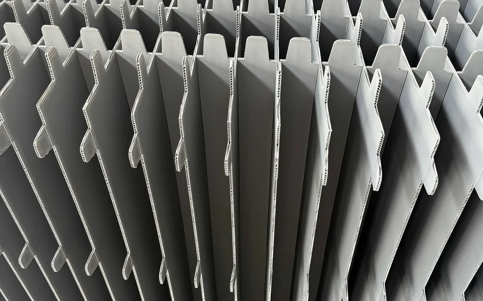 Grey slotted corrugated polypropylene divider panels prepared for assembly