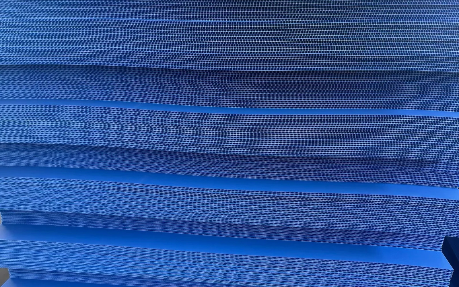 Blue PP corrugated plastic sheets stacked with twin-wall flute edges visible.